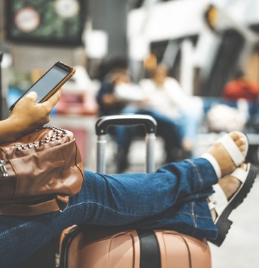 Woman Checking Phone Resting on a Suitcase 