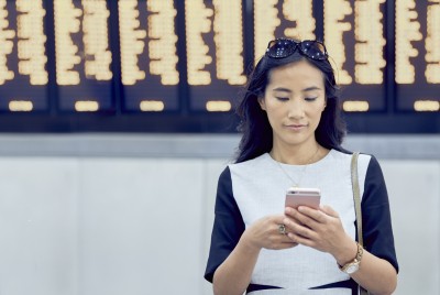 woman_checking_phone_in_airport_in_front_of_screen.jpg